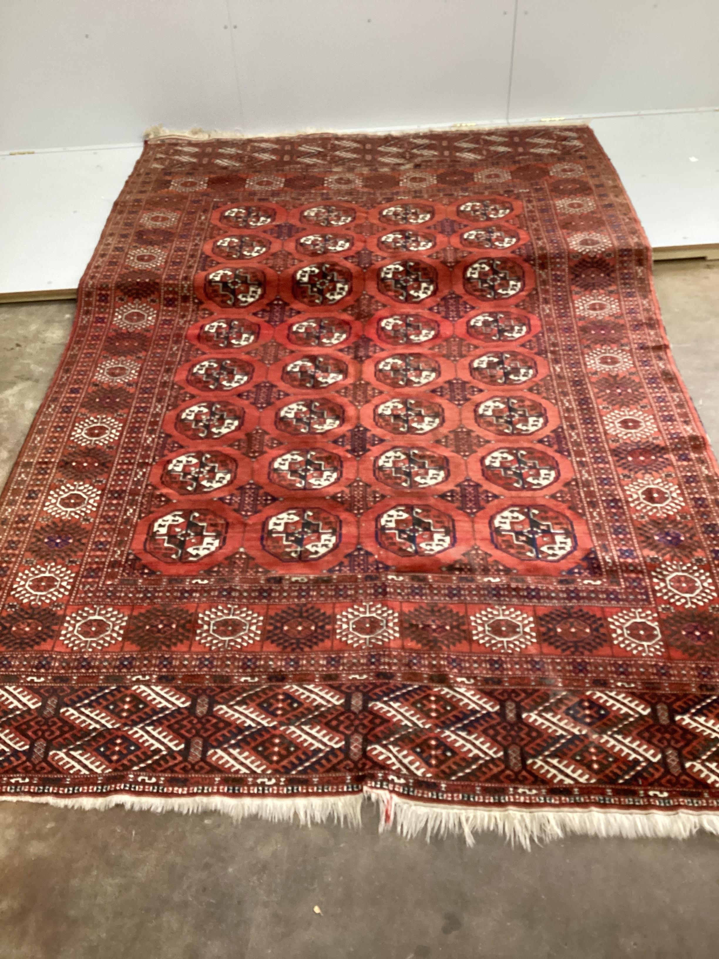A Bokhara red ground carpet, woven with rows of elephants foot, 308 x 203cm (Worn at one end)